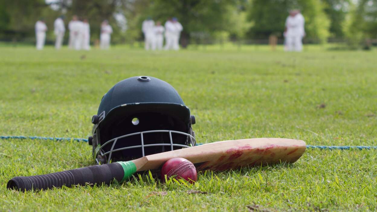 Cricket helmet, bat and ball on boundary line during a game