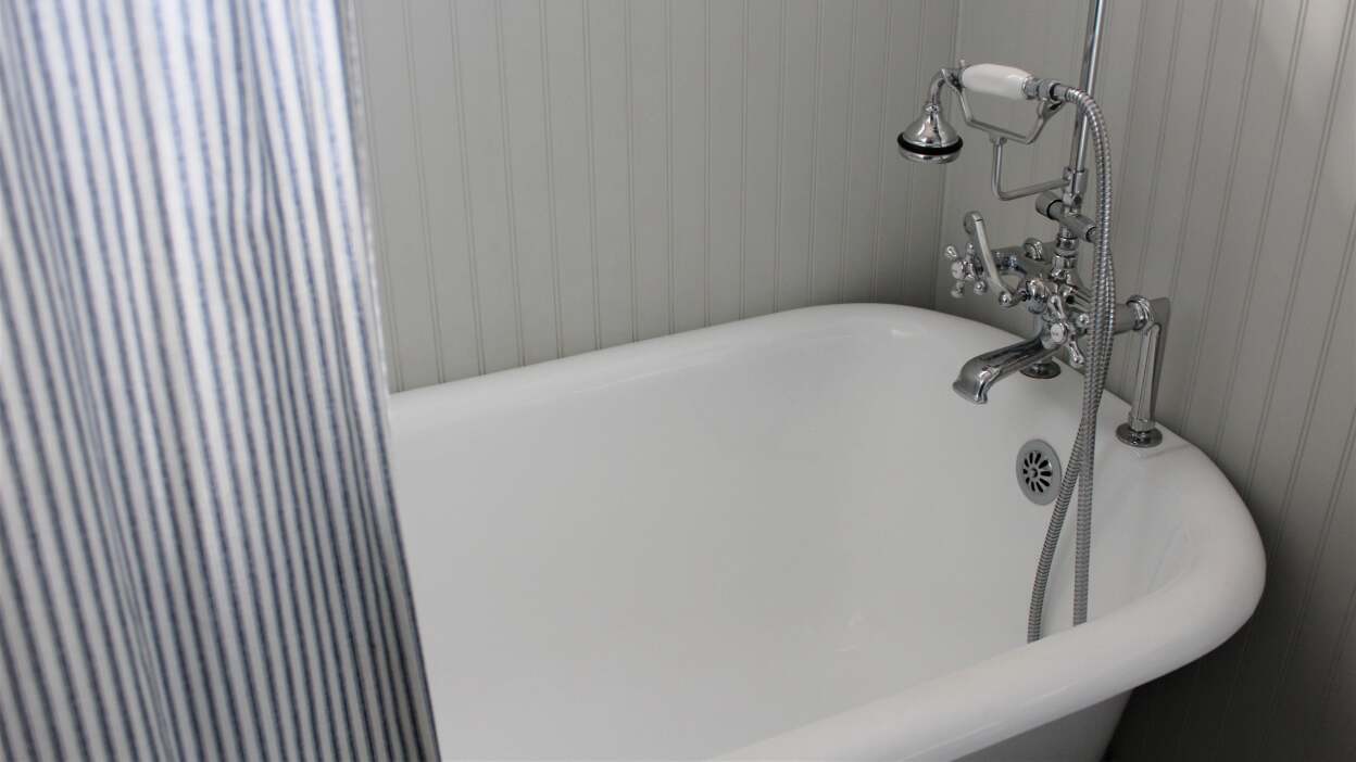 A white clawfoot bathtub with older silver fixtures