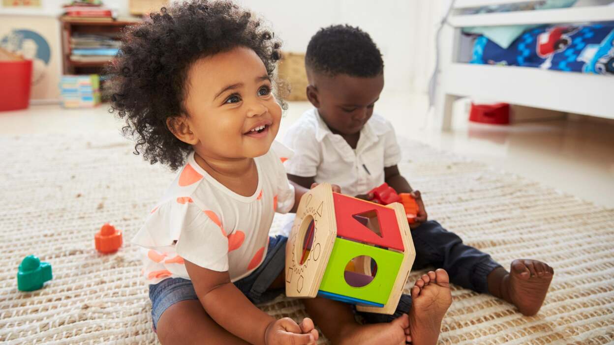 two toddlers playing with toys on the floor