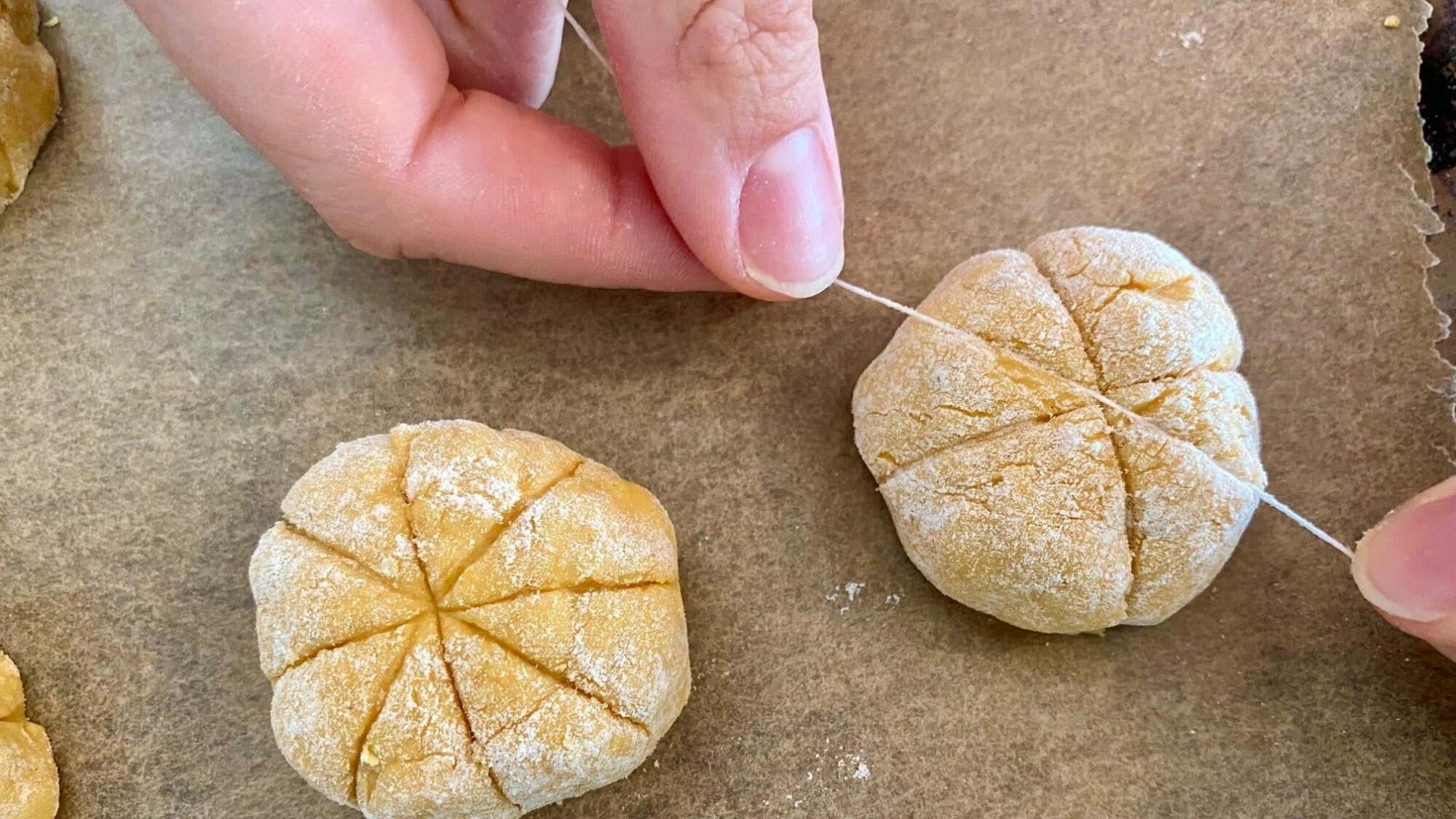 Hands pressing a piece of dental floss into the gnocchi. 