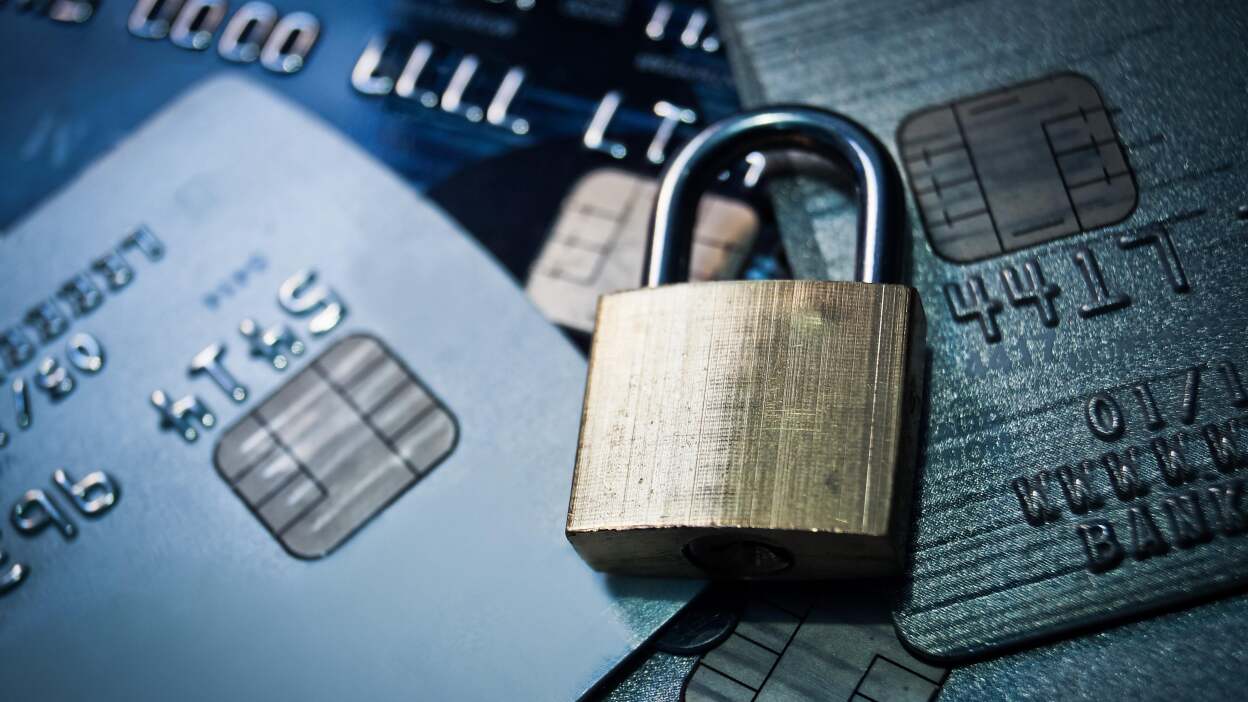 A locked padlock sits atop a pile of credit cards 