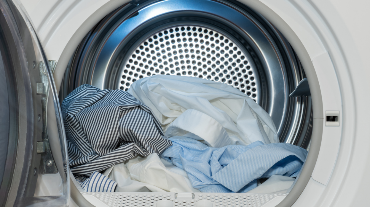 An open dryer with a pile of clean clothes inside