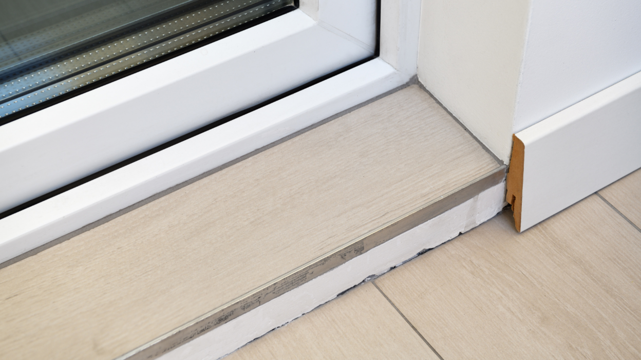 Skirting board is poorly installed, uneven cut. The transition between the floor and the threshold.