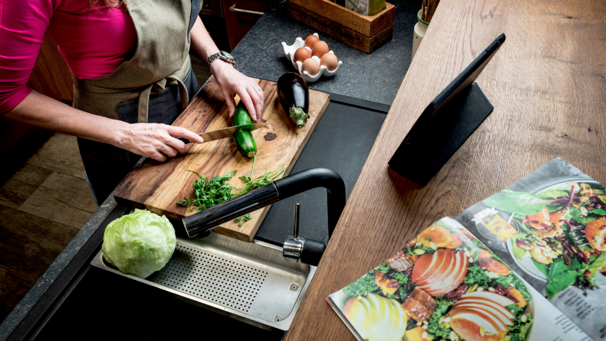 woman chopping vegetables with open magazine with recipe nearby