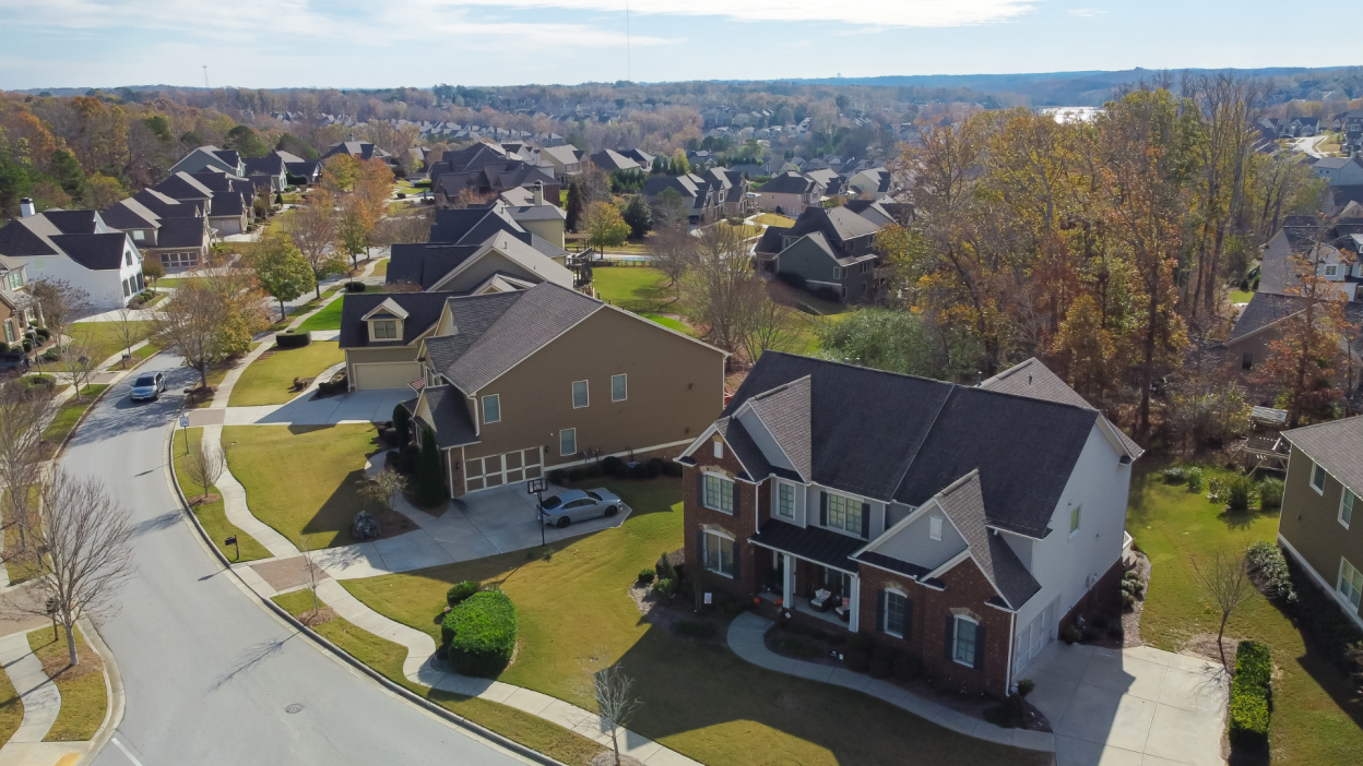 A zoomed-out photograph of a pretty, organized suburban neighborhood with green lawns