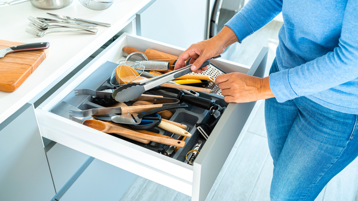 woman sorting through drawer of cooking utensils