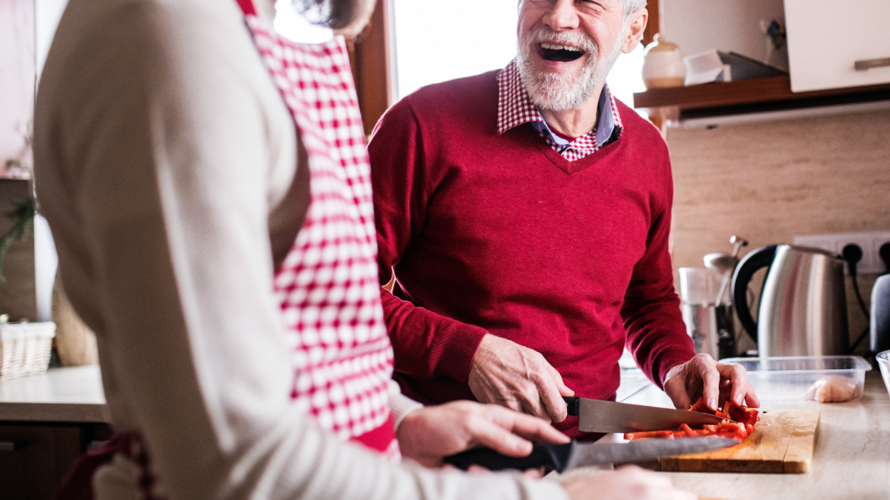 An older man and a younger man cooking together in a kitchen