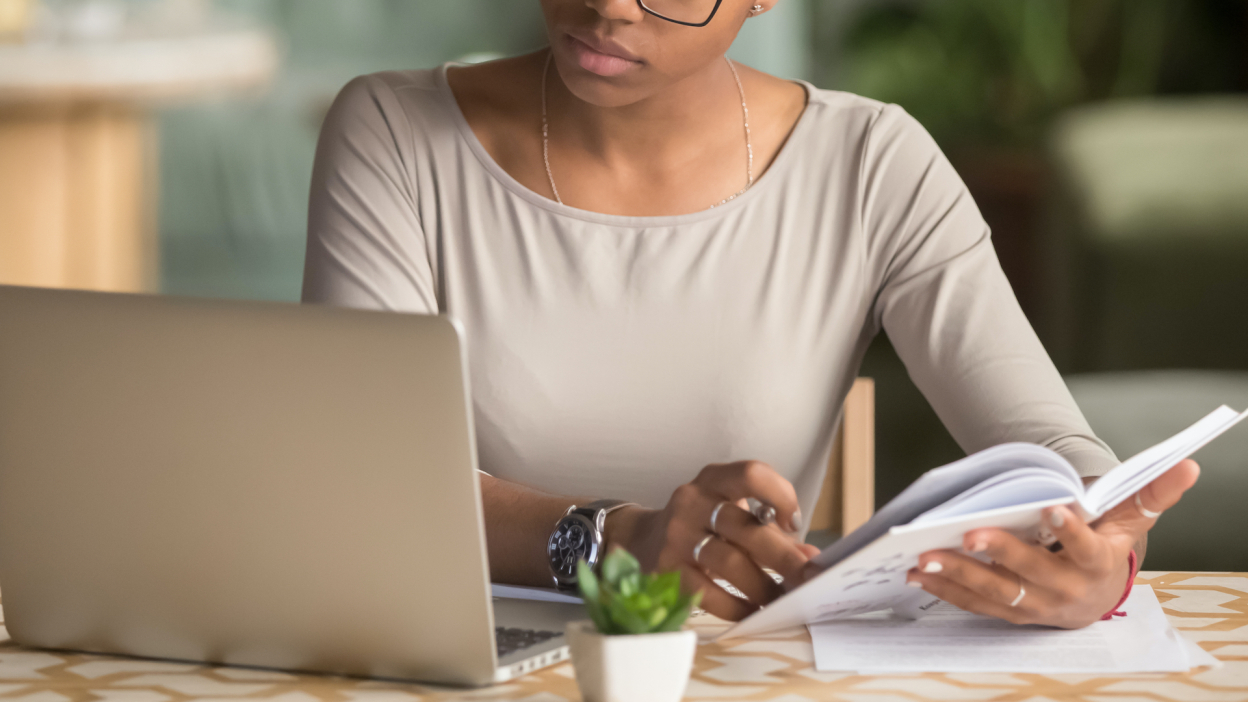 person looking at laptop and notebook