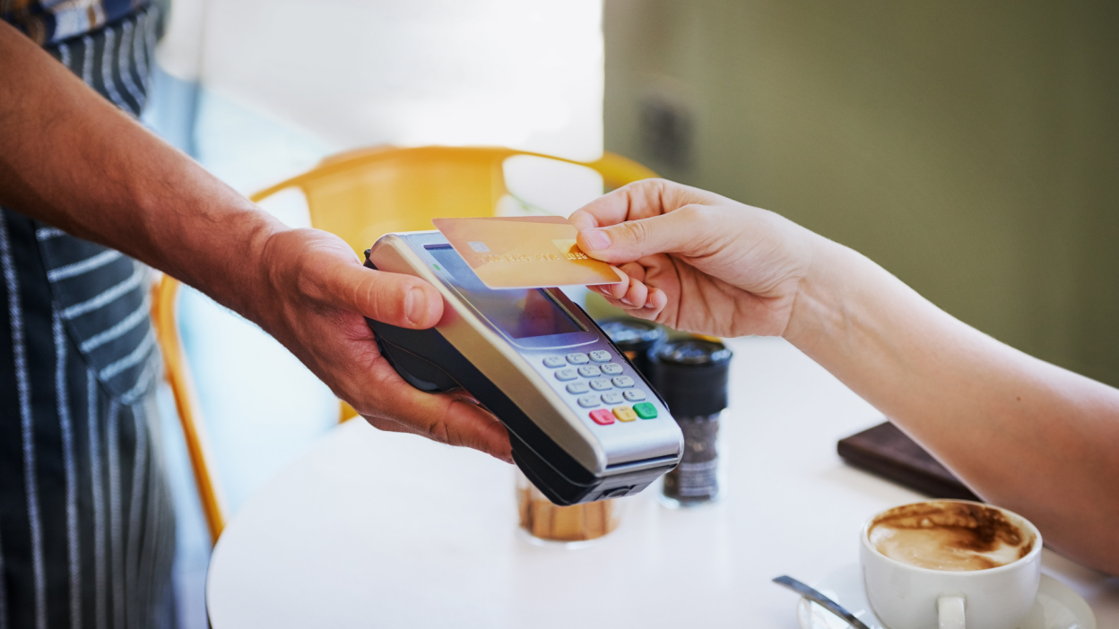 person using "tap to pay" with credit card at coffee shop