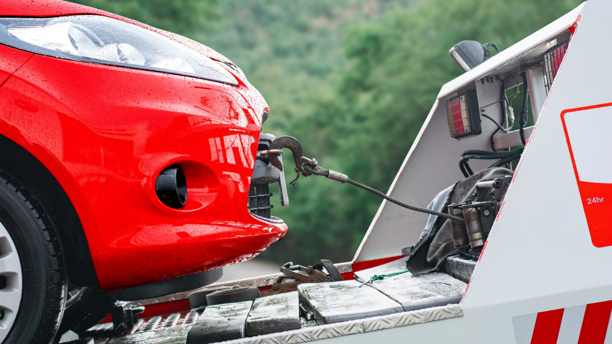 Red car being loaded into a tow truck