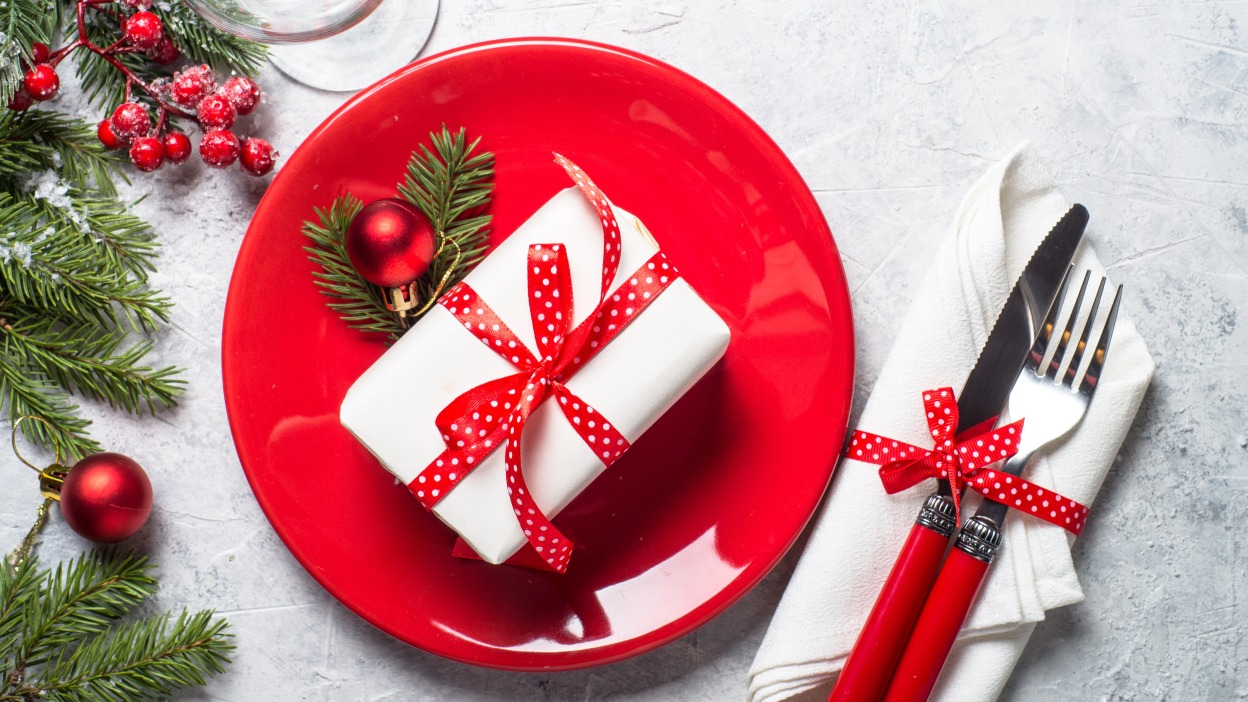 A wrapped present on a plate next to some silverware.