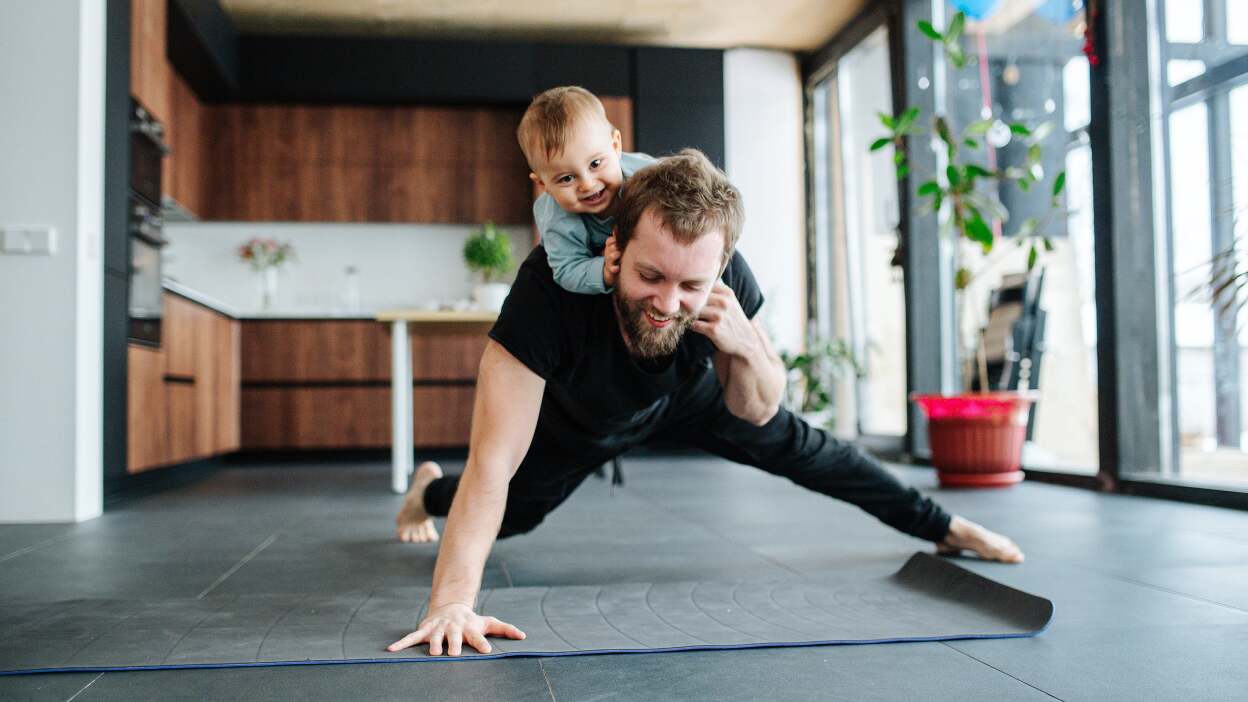 dad doing one-armed pushups in the kitchen with kid on back